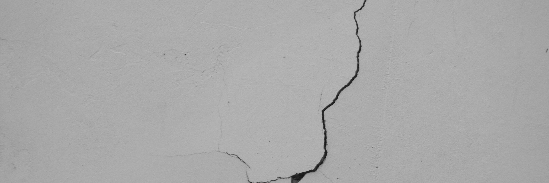 Fissure sur un mur enduit blanc