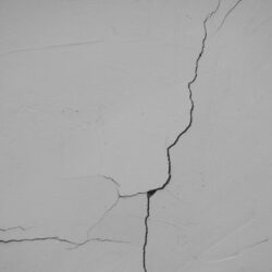 Fissure sur un mur enduit blanc