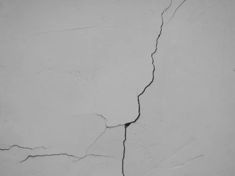 Fissure sur un mur enduit blanc