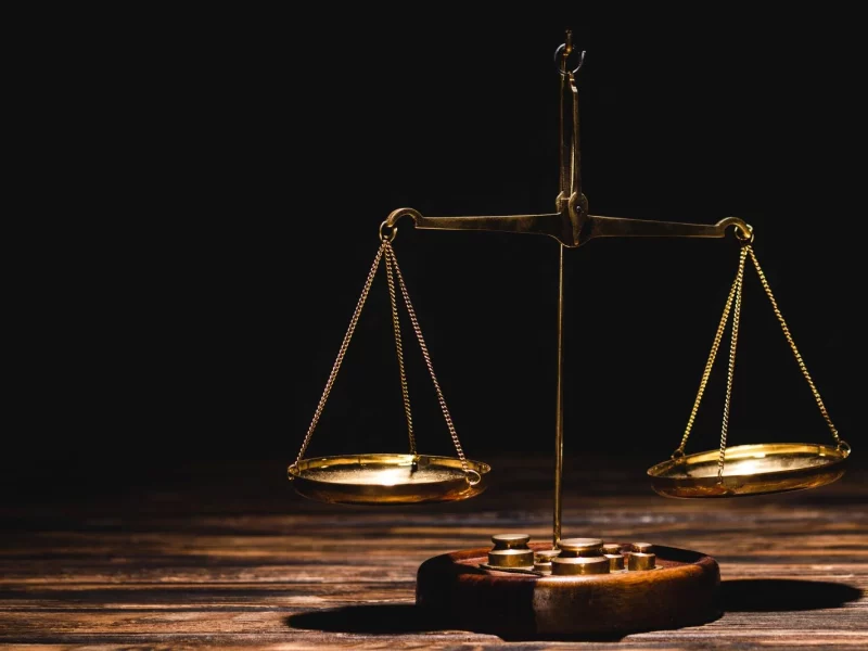 golden scales of justice on wooden table on black background